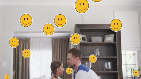 Animation-of-smiley-faces-over-happy-caucasian-father-and-daughter-jumping-at-home