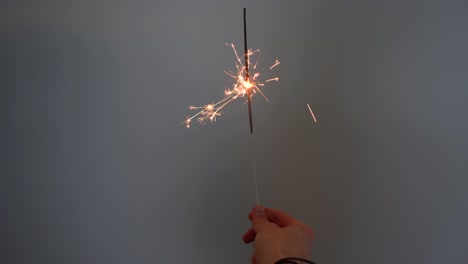 Young-Man-Holding-a-Sparkler-Against-Grey-Background