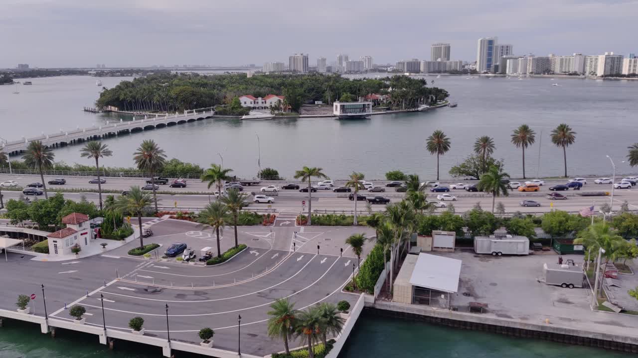 팜 아일랜드 앞의 움직이는 자동차와 교통이 있는 도로의 영화적 전망과 배경 조감도의 도시 경관 | 플로리다의 도로와 팜 아일랜드가 있는 도시의 드론 샷