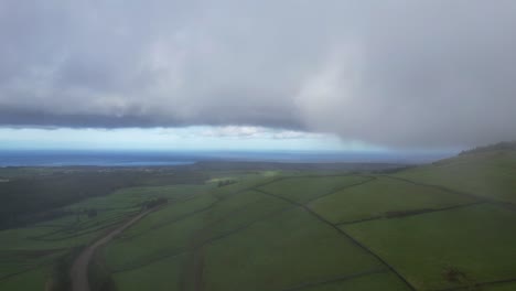 aerial of foggy and cloud covered landscape of farm fields in serra do cume, azores