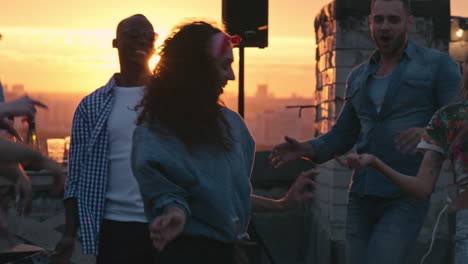 grupo de amigos disfrutando de una fiesta en una terraza al atardecer, todos bailan y ríen