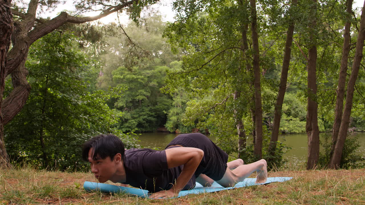 hombre con ropa deportiva haciendo yoga en una alfombra en el bosque junto a un lago o río disfrutando de la paz y la belleza de la naturaleza 5