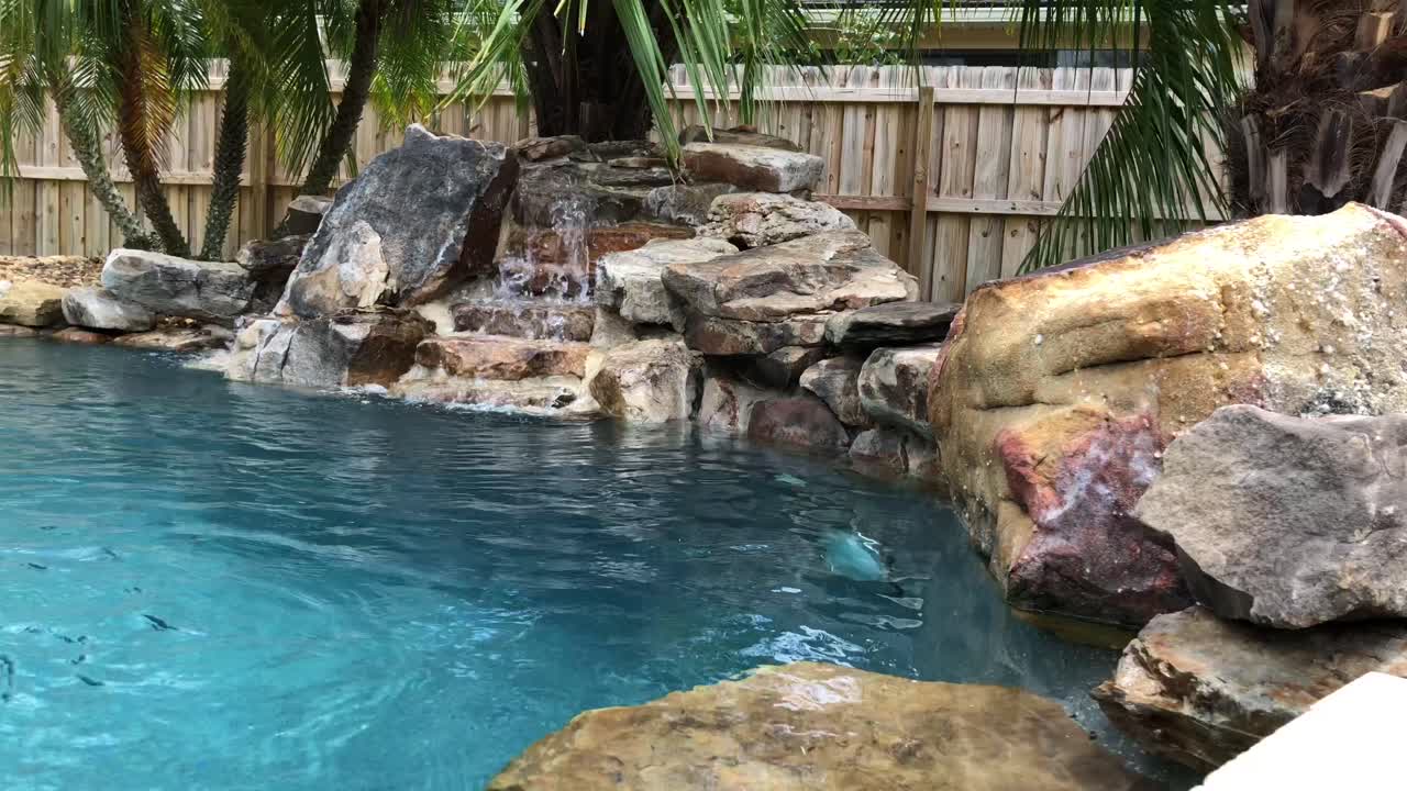 야자수, 푸른 소금물, 거품이 이는 폭포가 있는 평화로운 야외 수영장