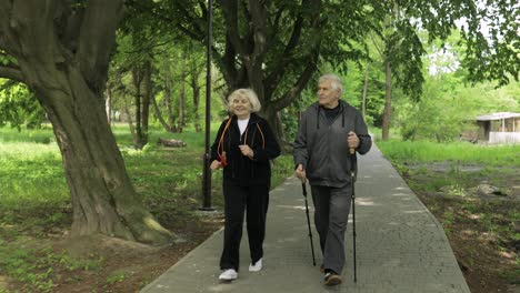 active senior old couple. man training nordic walking, woman running in park