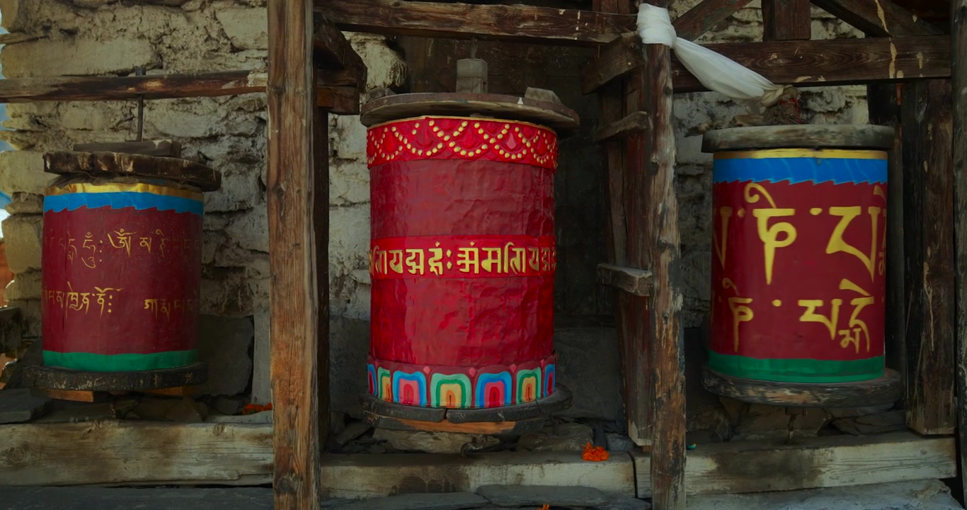 Annapurna Circuit, Manang, Nepal. Perinteisiä käsinmaalattuja buddhalaisia rukousmyllyjä puukehyksessä kiviseinää vasten