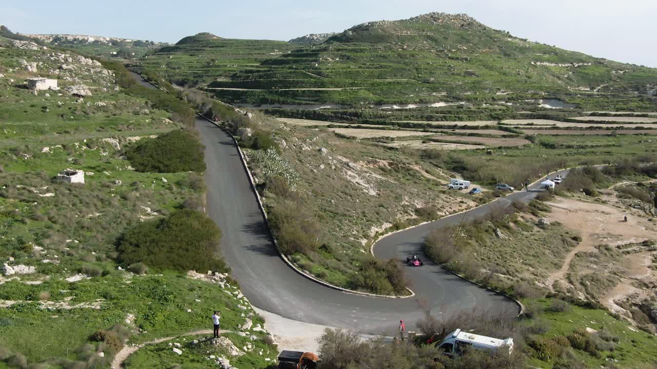 Pink Race Car Driving On The Curved Road Track On A Sunny Day - Aerial Shot