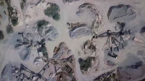 vista aérea de una cantera de piedra en funcionamiento con trituradoras de piedra, excavadoras, camiones en un entorno natural con luz del día