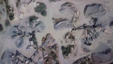 aerial view of a working stone quarry with stone crushers, bulldozers, trucks in a natural environment with daylight