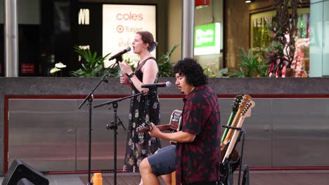 duo playing guitars and singing outdoors