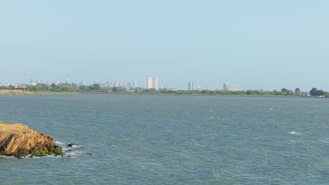 an ascending aerial view of the albany shore with downtown oakland and berkeley skyline in the distance.
