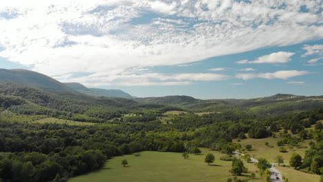 drone aéreo disparado sobre una carretera extraurbana en el valle del bosque, escena campestre-1