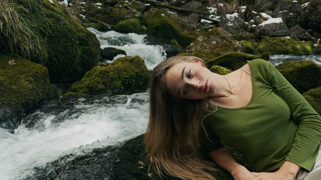 женщина отдыхает у горного ручья.