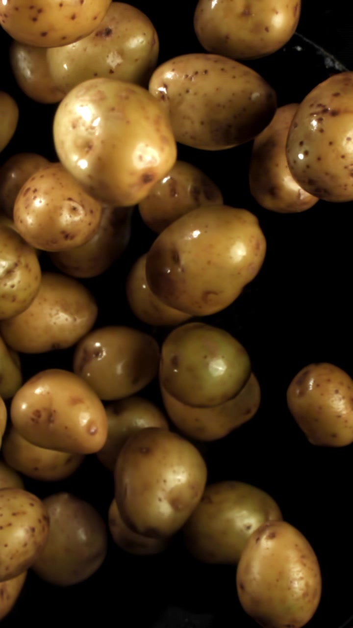 Patate fresche e crude che cadono al rallentatore su sfondo nero