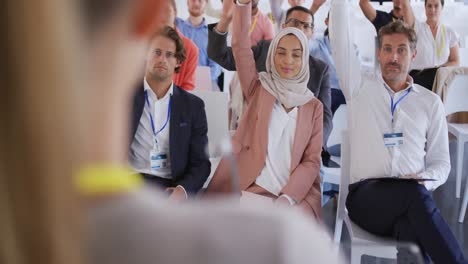 audience at a business presentation raising their hands to ask questions