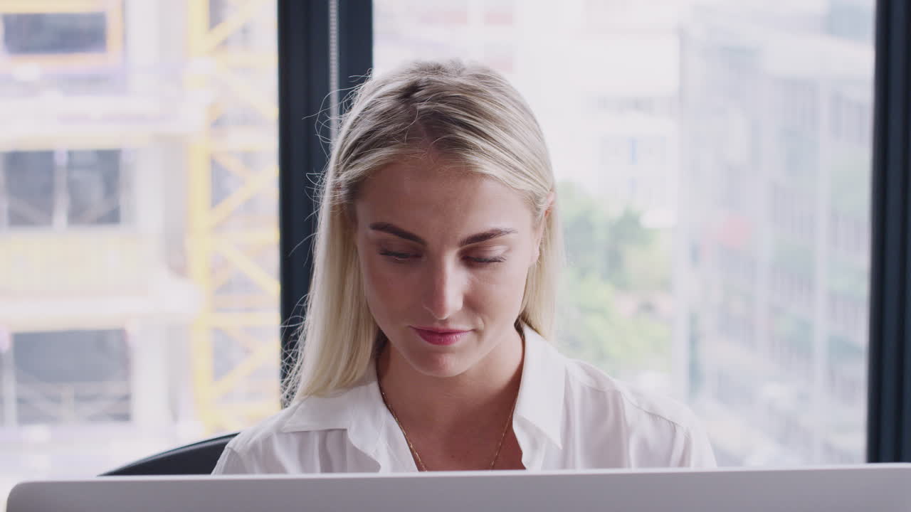 rubia de cabello blanco mujer creativa trabajando en el monitor de la computadora en la oficina, bebiendo café, de cerca