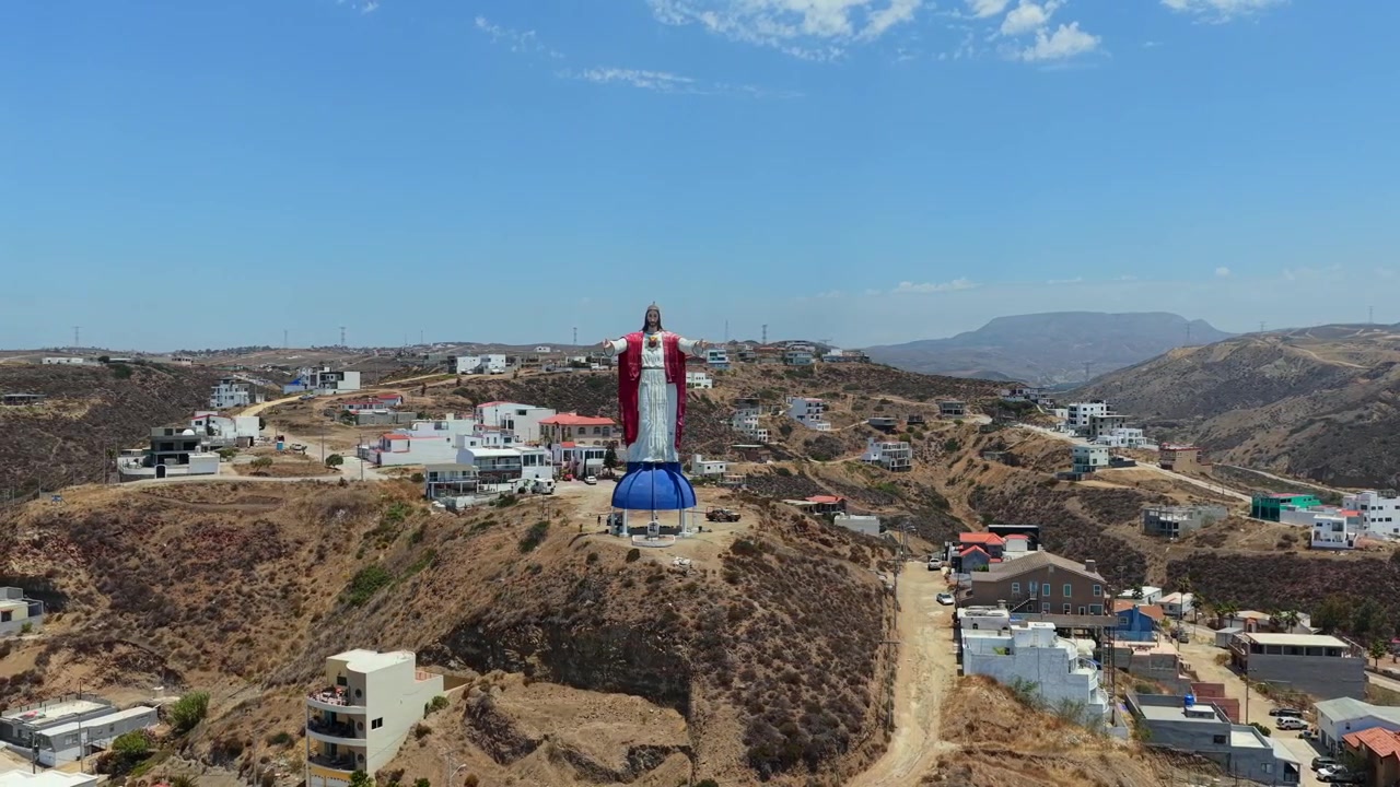 Veduta aerea del monumento Cristo del Sagrado Corazón che domina le colline di Rosarito, Bassa California, Messico, con i quartieri residenziali circostanti.