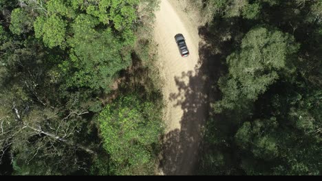Aerial-of-a-four-wheel-drive-taking-a-turn-on-a-path-in-a-forest-during-an-adventure-camping-road-trip