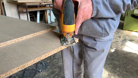 carpintero cortando un trozo de esquina de un tablón de madera en un taller de carpintería