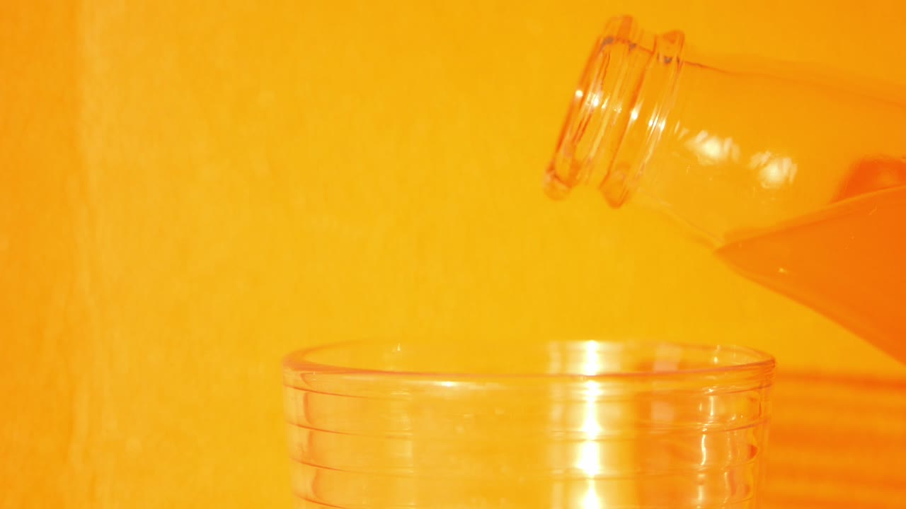 Orange liquid being poured from a bottle into a glass