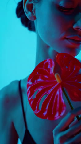 artistic portrait of a woman with red anthurium under blue and red light