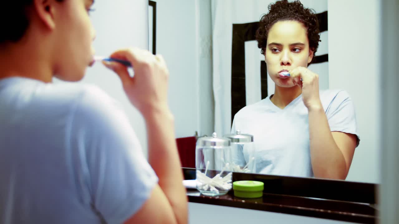 Woman brushing her teeth in front of the mirror 4k