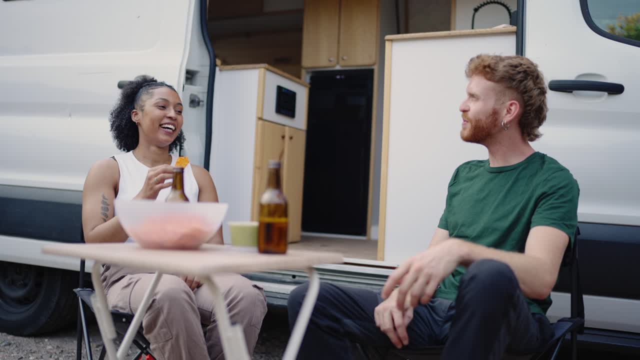 Two people sitting at a table next to a van