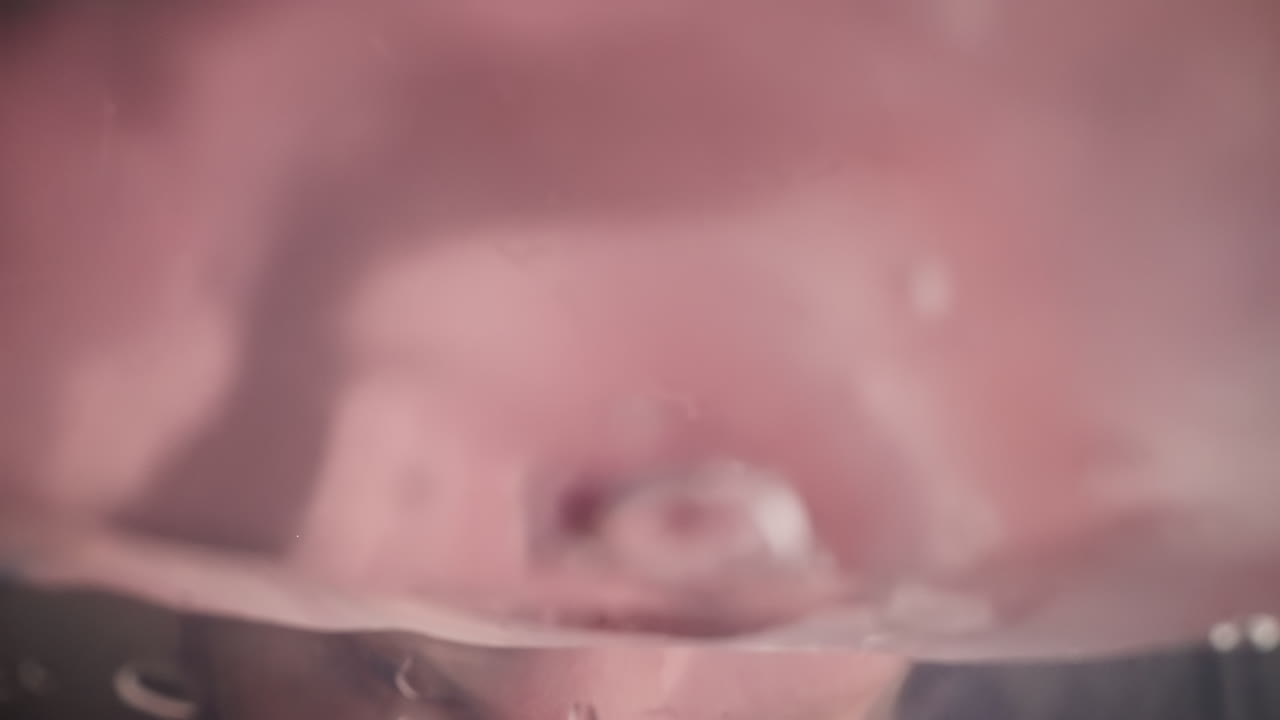 Una persona assetata beve una dolce bevanda rosa direttamente dalla bottiglia.