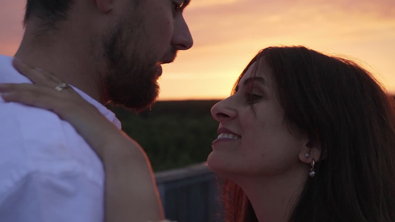 Couple kissing each other while the sun is setting behind them.