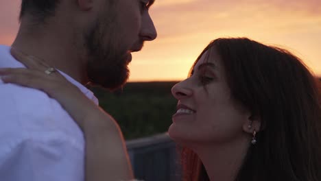 couple kissing each other while the sun is setting behind them.
