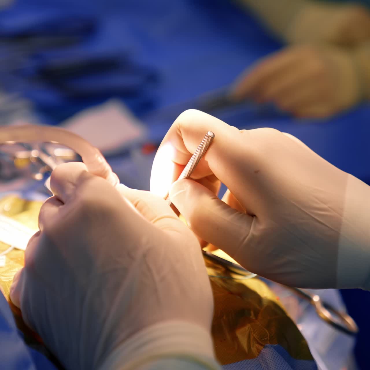 Neurosurgeon's hands in gloves use long thin metal tool. Doctor changes the instrument on electric device. Close up