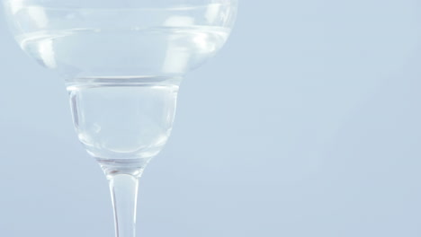 video de aceitunas cayendo en un vaso de martini sobre un fondo blanco