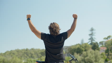 vista posterior de un atleta con discapacidad levantando las manos en el parque