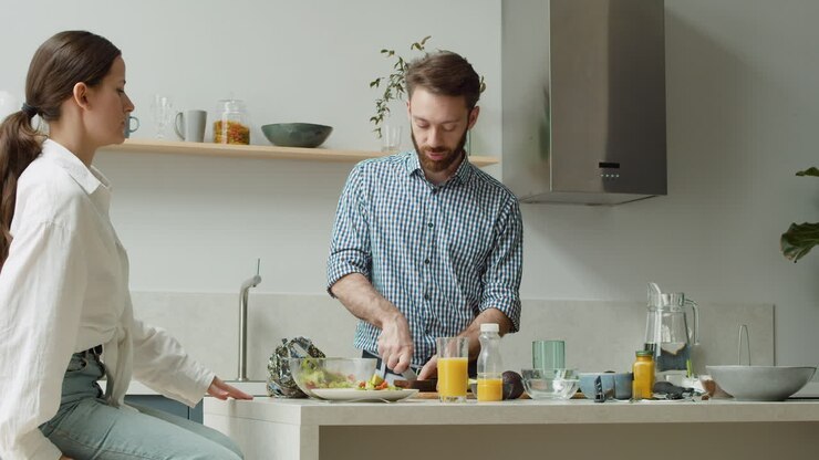 Coppia felice che chiacchiera e prepara il pranzo insieme in una cucina moderna