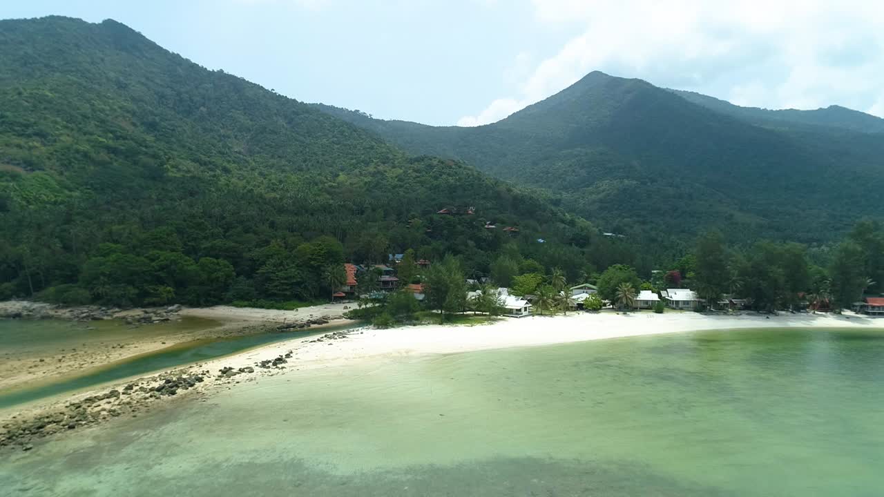 casas en la playa de arena blanca con fondo de selva y montaña, vista aérea