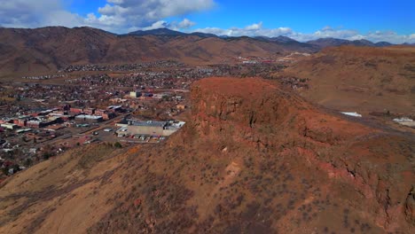 winter morning front range coors beer factory lookout north table mountain downtown golden colorado aerial drone denver suburbs neighborhood city sunny blue sky snow on hills forward upwards motion