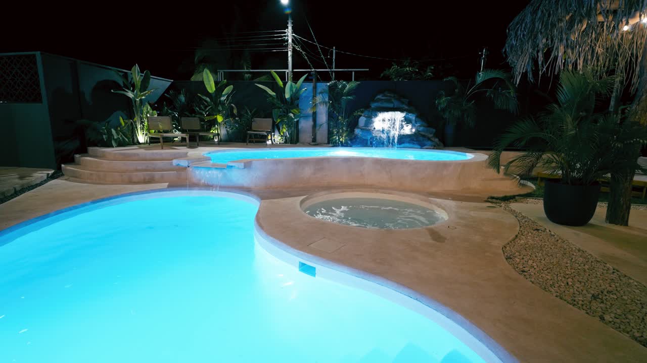 Luksusresort swimmingpool med vandfald og boblebad om natten