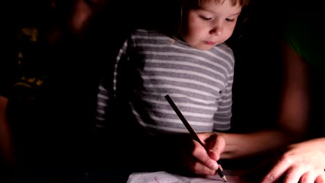 madre muestra a los niños cómo dibujar una flor con un lápiz en una hoja de papel, primer plano