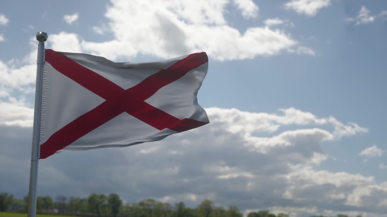 bandera de alabama en un asta de bandera ondeando en el viento en el cielo. estado de alabama en los estados unidos de américa