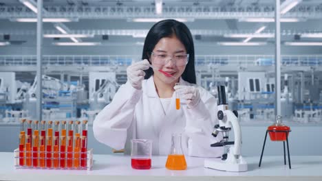 asian woman scientist making experiment with test tube on the table with microscope in the laboratory. carrying out experiments, working in the lab analyzing her finding samples test tube