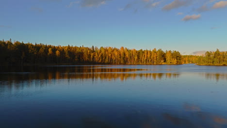 Flying-low-over-a-body-of-water-and-climbing-up-to-reveal-an-endless-forest-and-Fiskträsk-lake-in-Sipoonkorpi-National-Park-in-Finland