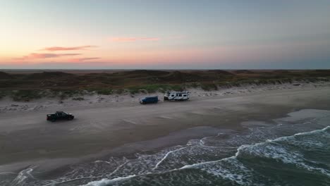 vehículo conduciendo a través de la orilla arenosa de la playa en la isla del padre, texas, ee.uu. - toma aérea de drones