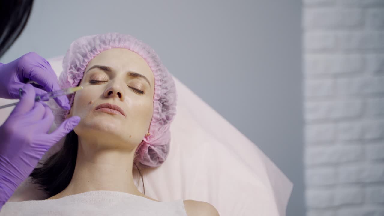 A client are laying with her eyes closed in the chair during a lip augmentation procedure. Botox. Beauty injections. Close-up.