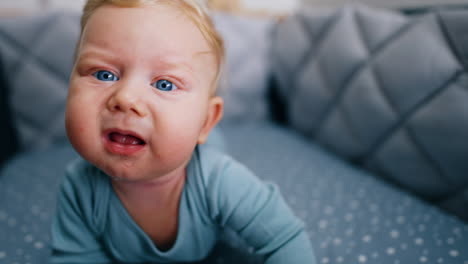 sweet caucasian blond baby boy lying on the belly. curious little kid trying to reach the camera. close up.