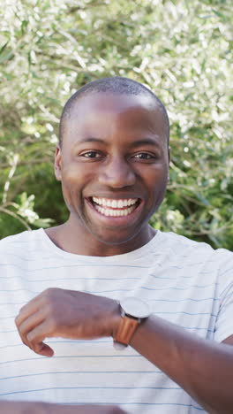 vertical video: crossing arms and smiling, man outdoors enjoying sunny day