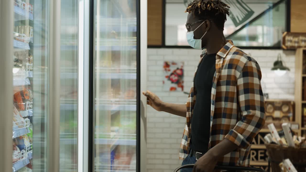 아프리카계 미국인 쇼핑객 이 식료품 가게 의 냉장고 에서 음식 을 선택 하고 있다