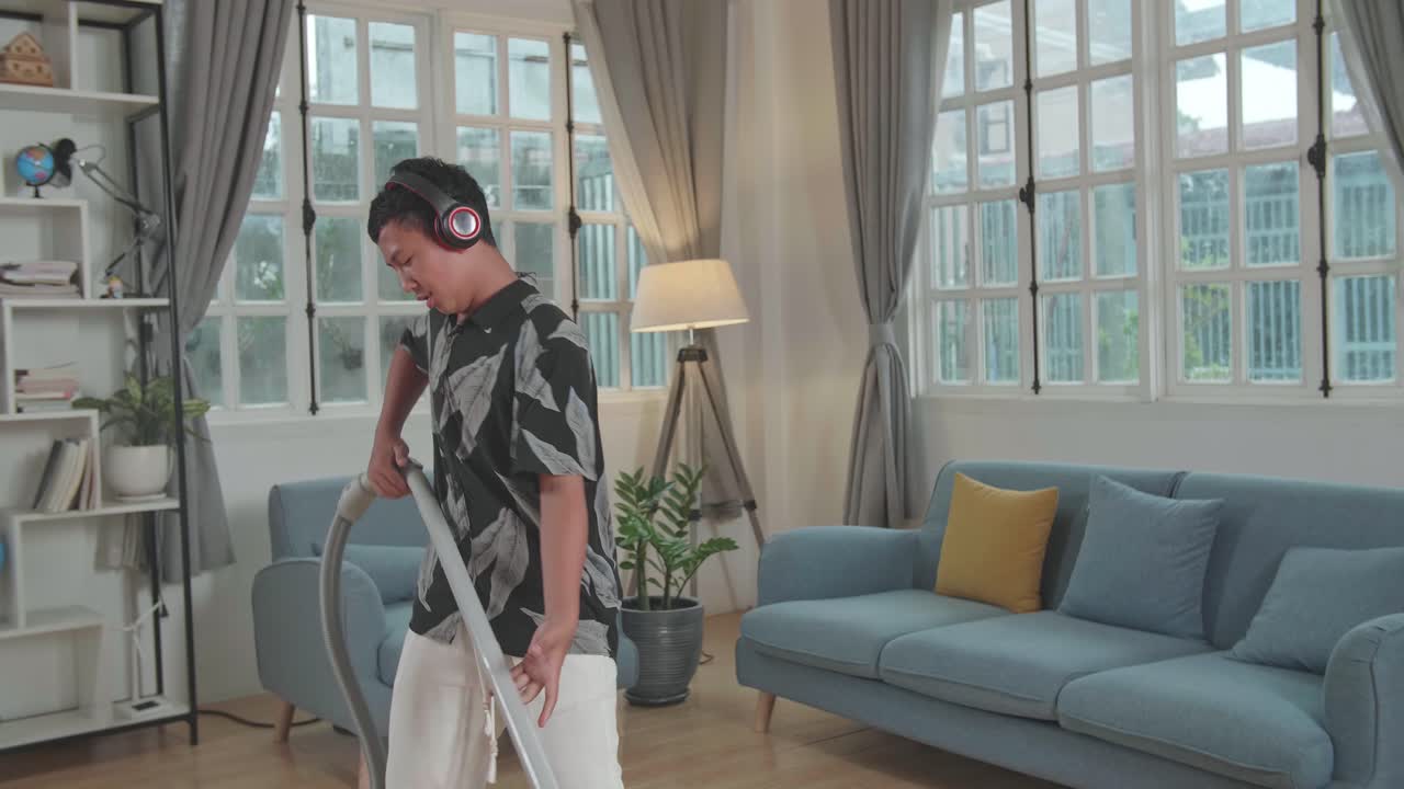 Cheerful Boy Cleaning Up His Home And Singing, He Is Using The Vacuum Cleaner As A Guitar And Microphone