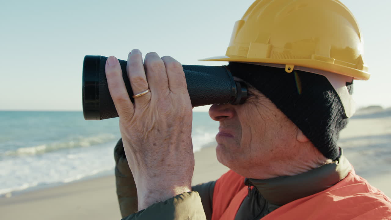 Engineer Using Binoculars to Observe Something In The Ocean