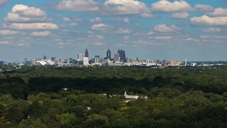 Toma-Aérea-Amplia-Que-Muestra-El-Bosque-Verde-Y-El-Horizonte-De-La-Ciudad-De-Atlanta-Durante-Un-Día-Soleado-En-Estados-Unidos---Vista-Desde-El-Distrito-Suburbano