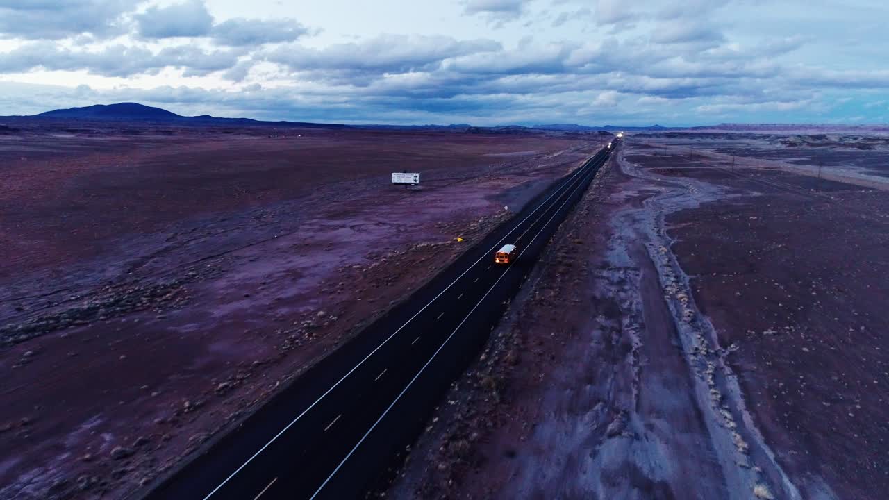 Vol de drone en avant au-dessus d'une route de soirée traversant un vaste désert, États-Unis.