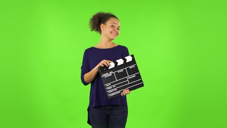 mujer con clapperboard en la pantalla verde